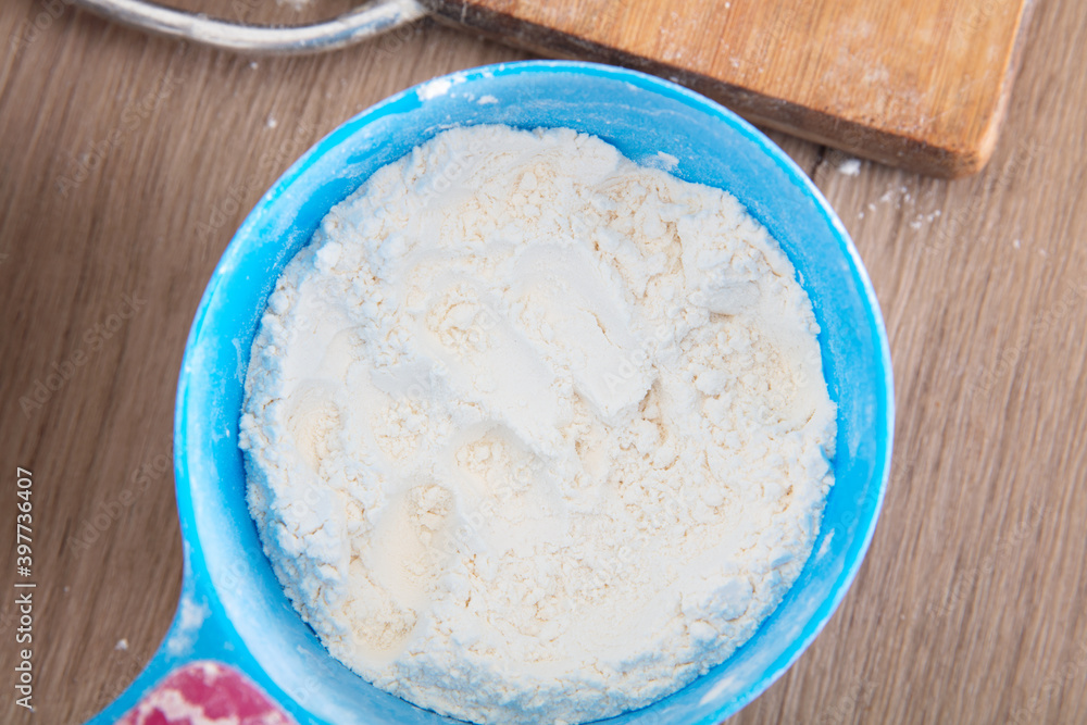 Looking down and shooting a plastic scoop full of white flour on the table Looking down and shooting a plastic scoop full of white flour on the table
