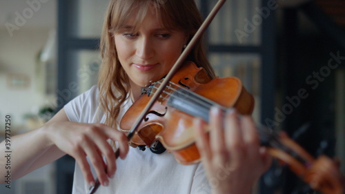 Woman learning to play violin at home. Romantic girl playing violin with bow