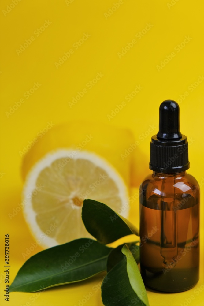 Vitamin C. Serum with vitamin C. Lemon essential oil.glass bottle with a pipette, fresh cut lemon with leaves on a bright yellow background. Health and beauty concept.Organic Natural Cosmetics Vitamin C. Serum with vitamin C. Lemon essential oil.glass bottle with a pipette, fresh cut lemon with leaves on a bright yellow background. Health and beauty concept.Organic Natural Cosmetics
