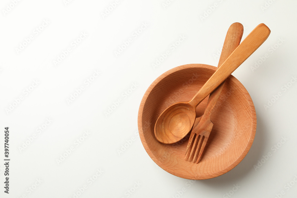 Wooden bowl with fork and spoon on white background