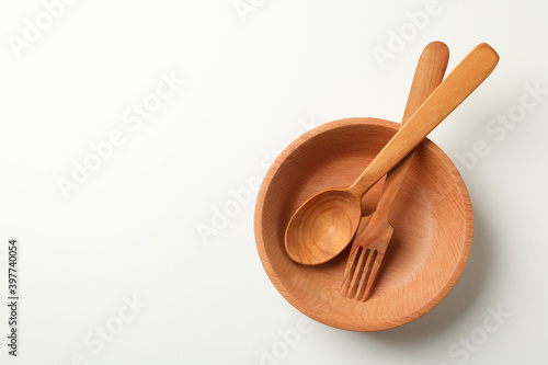 Wooden bowl with fork and spoon on white background