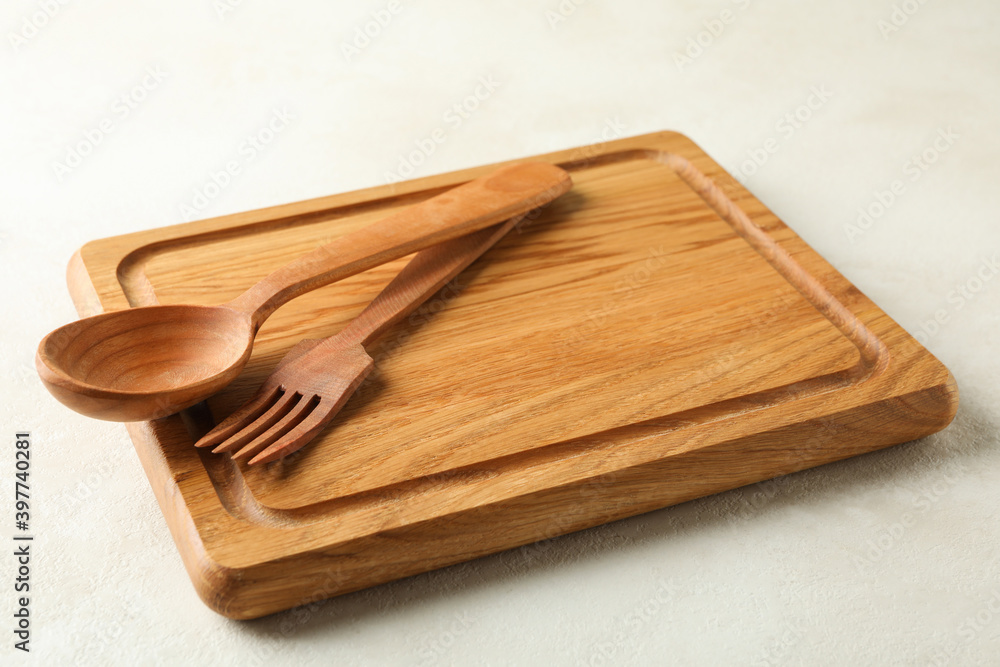 Wooden board and cutlery on white background