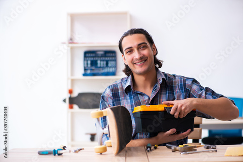 Young man repairing skateboard at workshop