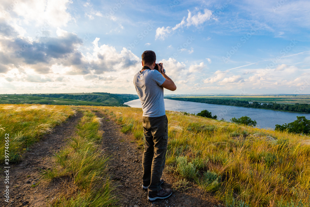 Back view of a photographer taking pictures of river landscape
