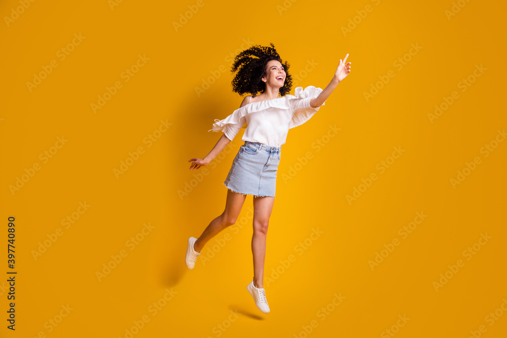 Full size photo of cute cheerful brunette woman jumping see something wear top skirt isolated on yellow color background
