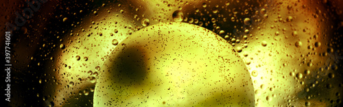 Abstract yellow ball with small black dots against a blurred background covered with drops, monochrome.