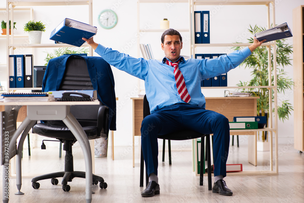 Young male employee doing sport exercises at workplace Young male employee doing sport exercises at workplace