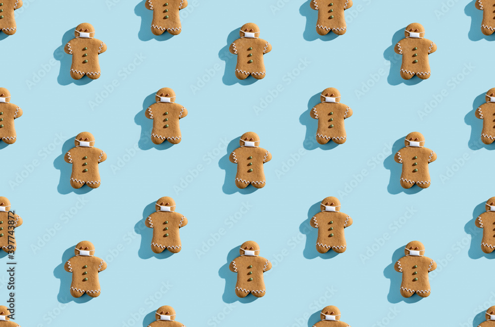 Fototapeta premium Pandemic gingerbread man pattern. Conceptual pastry design. Festive bakery illustration. Decorated icing figure biscuits in protective mask isolated on blue pastel.