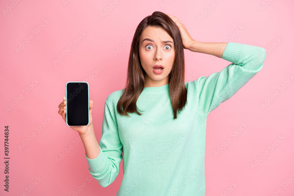 Photo of shocked lady hold telephone screen empty space hand head wear teal pullover isolated pink color background Photo of shocked lady hold telephone screen empty space hand head wear teal pullover isolated pink color background