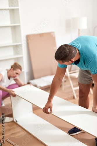 Husband and wife assembling new furniture - renovation home concept.