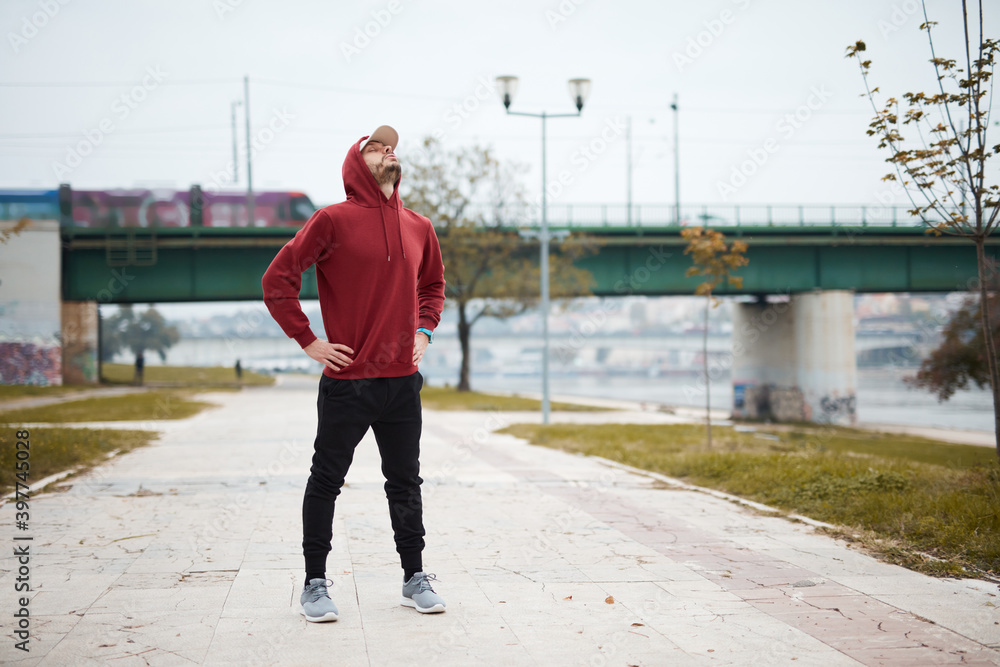 Athletic sporty man training in hoodie sweatshirt in urban city park. Athletic sporty man training in hoodie sweatshirt in urban city park.