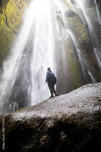 A man in front of a waterfall in a cave in Iceland