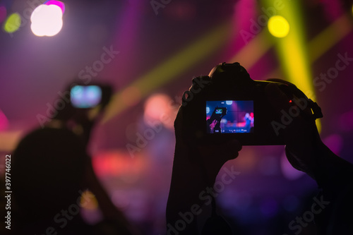 Someone's dslr camera with the shooting a concert with the live view picture on a screen. Music band on a stage as an object of shooting.