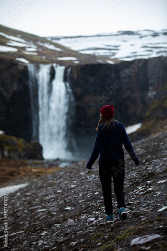 A woman walking towards a waterfall in Iceland in winter