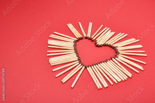 matchsticks in the shape of a heart on red background photo