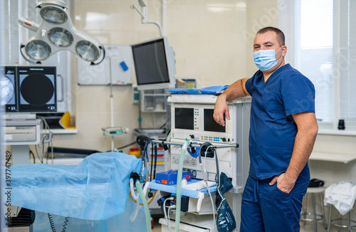 Doctor with medical mask on face. Modern medical equipment background. Hi tech operating room.