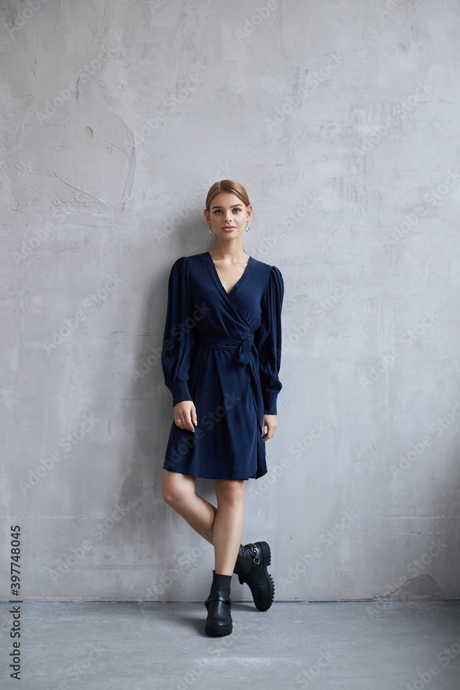 Sexy Fashion beautiful woman in dress is standing against the wall. Perfect makeup, romantic portrait of a blonde woman Sexy Fashion beautiful woman in dress is standing against the wall. Perfect makeup, romantic portrait of a blonde woman