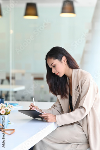 Portrait of creative designer woman is working on digital tablet at her workplace at modern office.
