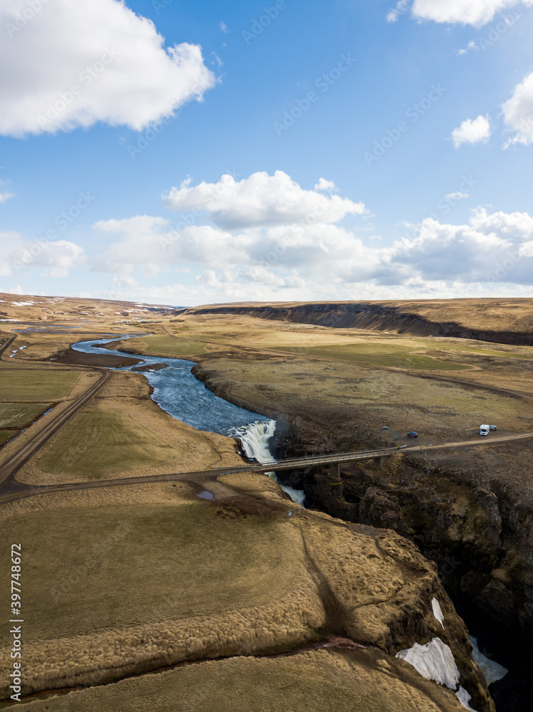 Aerial of a bridge and waterfall in Iceland in spring