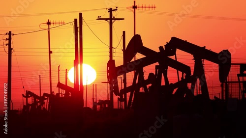 The sun rises behind oil pumps in California