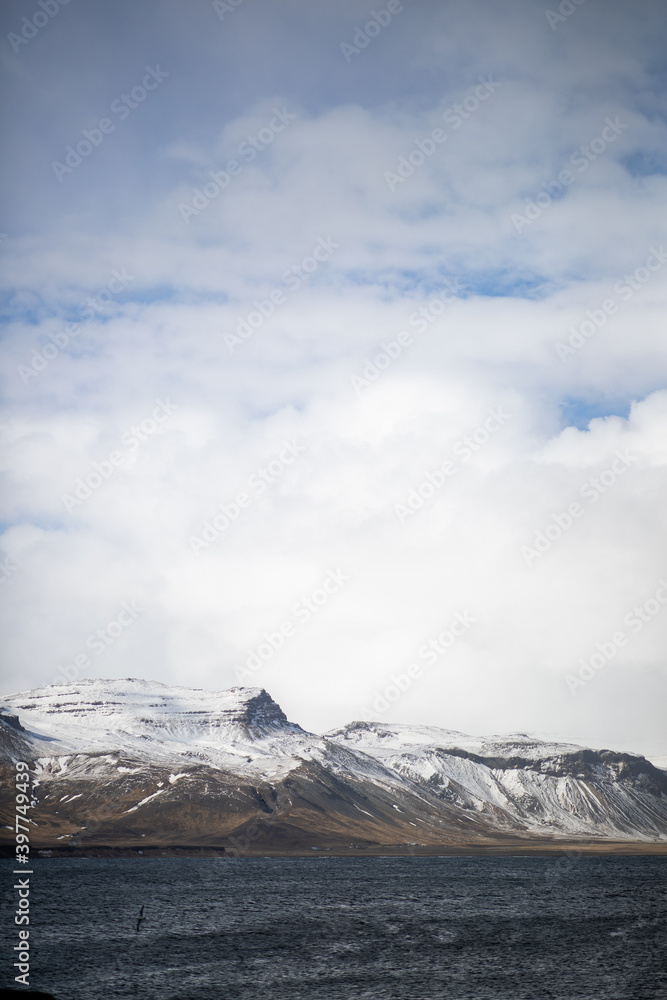 Landscape of snowy mountains and sea in Iceland on a cloudy day