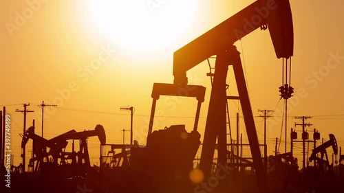 The sun rises behind oil pumps in California