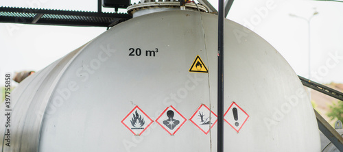Принти на полотні Huge fuel storage tank with danger symbols at gas station.