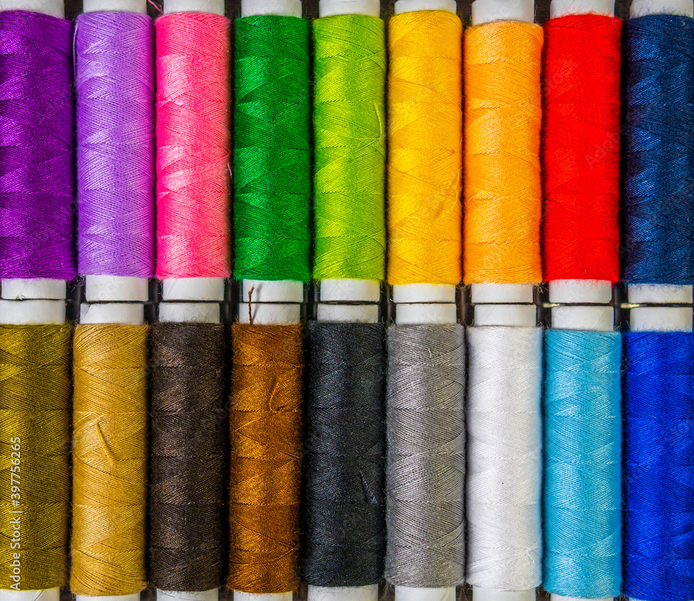 Colorful sewing threads on top of a gray cloth, top view Colorful sewing threads on top of a gray cloth, top view