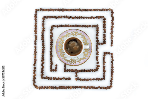 a cup on a saucer of black coffee with froth, surrounded by coffee beans