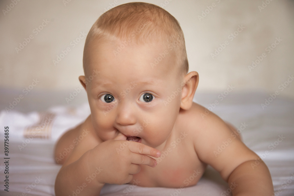 A charming boy licks his fingers while lying on his stomach. The view of a serious person A charming boy licks his fingers while lying on his stomach. The view of a serious person