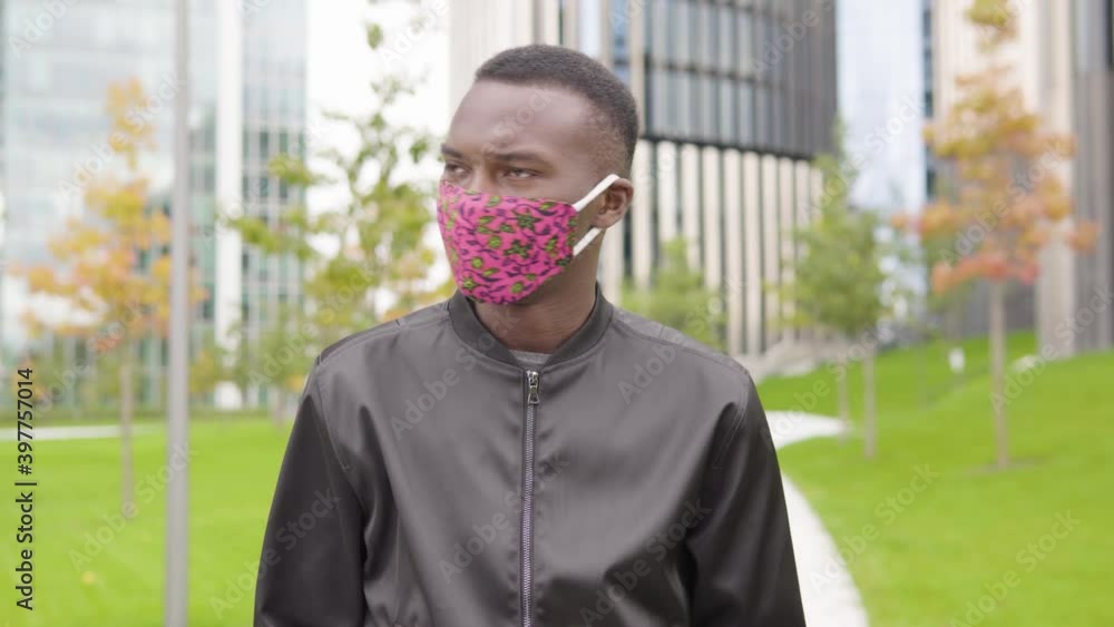 A young black man in a face mask acts upset and looks at the camera ...