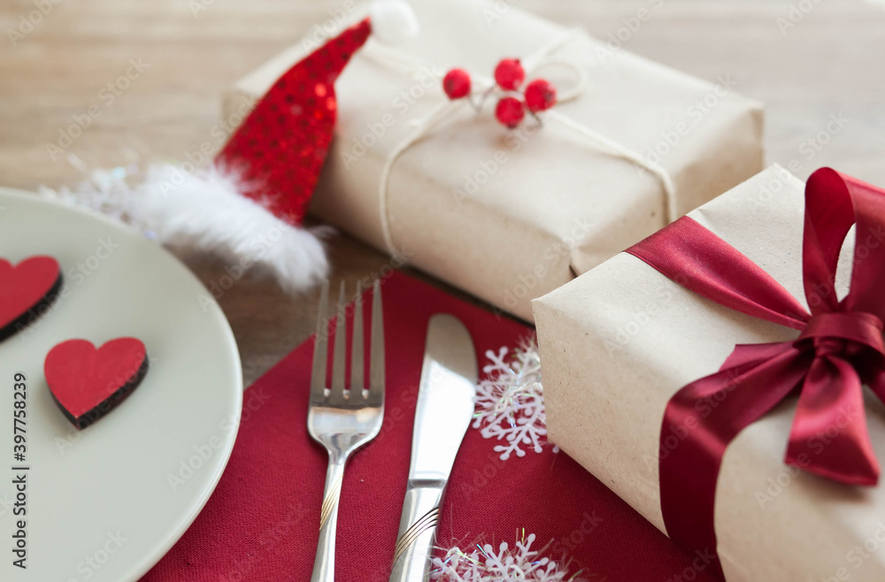 Festive table setting for Valentine's Day with plate, gift boxes, fork, knife and hearts on a wooden table. Festive table setting for Valentine's Day with plate, gift boxes, fork, knife and hearts on a wooden table.