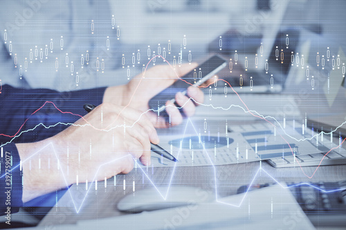 Double exposure of man's hands holding and using a digital device and forex graph drawing. Financial market concept.