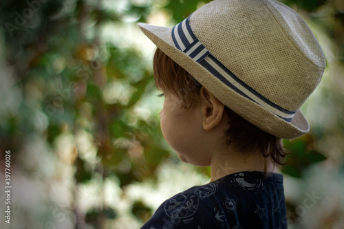 Stylish, happy child walks in the summer park in a straw hat