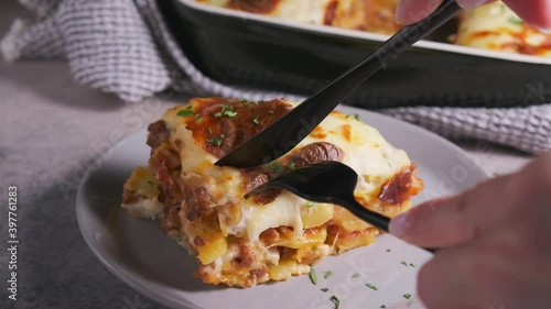 Eating Greek moussaka - potato and meat casserole with cheese, dark background. Greek food concept. photo