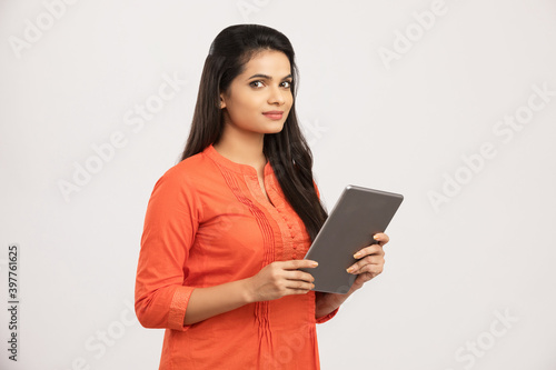 Worried Indian young woman holding digital tablet on white.