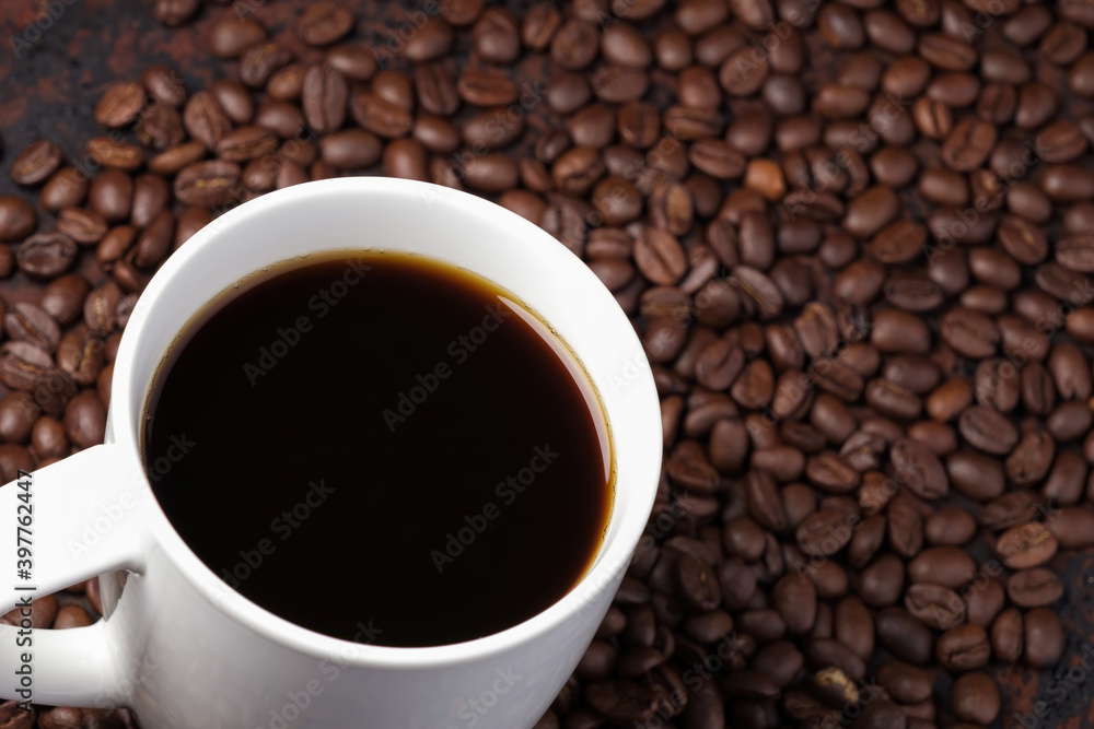 black coffee in white mug with surrounded by roasted coffee beans on dark red wood table black coffee in white mug with surrounded by roasted coffee beans on dark red wood table