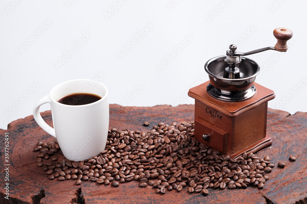fresh coffee in white cup with grinder and roasted seed on wood table isolated in white background