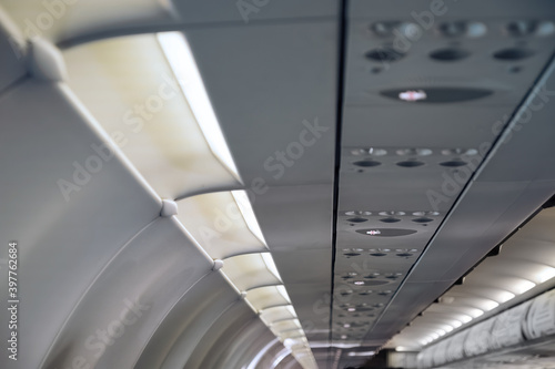 no smoking sign light up on ceiling of airplane cabin above passenger seat that mean cigarette is prohibited in flight.photo with noise and partly blured
