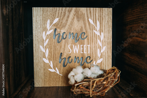 The inscription home sweet home is on a wooden basis. The inscription home sweet home on a wooden plank, stands on a wooden rack with a nest, symbolizes the home hearth, family happiness. Home Decor