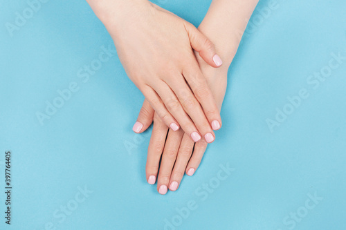 Manicure and nail care concept. Two woman hands with perfect pastel pink nail polish on aqua blue background. Summer minimal manicure. Flat lay, top view. Copy space. © Yulia Lisitsa