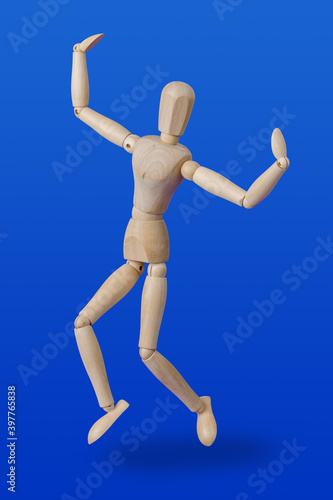 Dancing wooden toy figure on blue