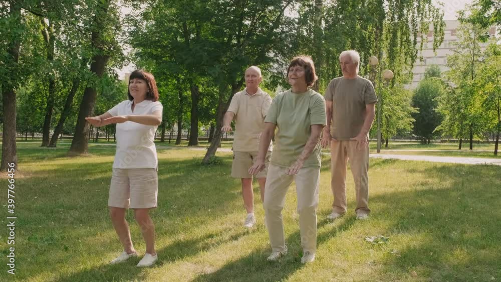 Wide shot of four adults practicing Qigong together in daytime in the park Wide shot of four adults practicing Qigong together in daytime in the park