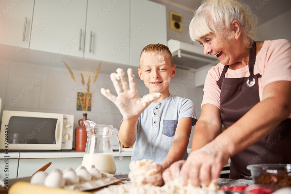 Joyful senior woman and her grandson preparing dough Joyful senior woman and her grandson preparing dough