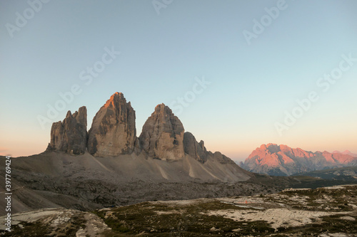 Golden hour in the Tre Cime region  Italian Dolomites. The mountains are shining with pink and orange. Sunrise in high mountains. Morning haze. Lower parts of the valley covered with shadow. New day