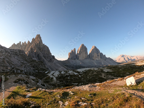 A panoramic capture of the Tre Cime di Lavaredo (Drei Zinnen) and surrounding mountains in Italian Dolomites. The mountains are surrounded by thick clouds. Early morning in the mountains. Daybreak