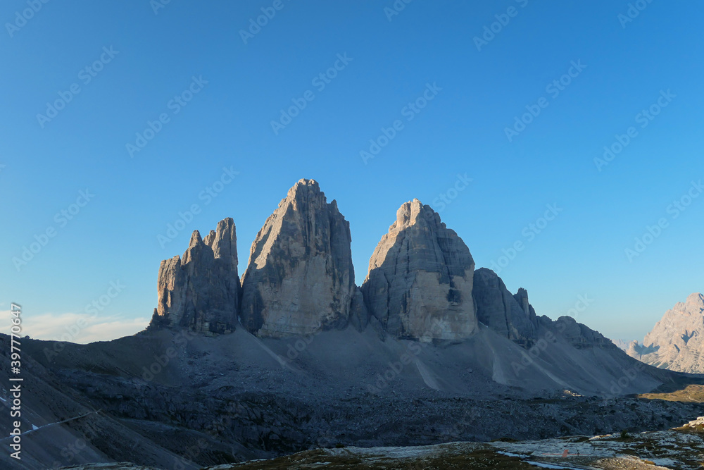 Golden hour in the Tre Cime di Lavaredo (Drei Zinnen) in Italian Dolomites. The mountains are reflecting golden sunrays. There is a lot of landslides and lose stones around. Natural wonder. Sunset