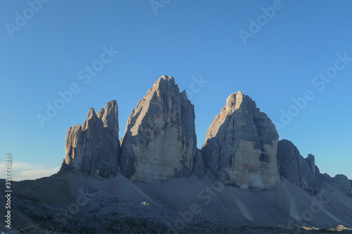 Golden hour in the Tre Cime di Lavaredo  Drei Zinnen  in Italian Dolomites. The mountains are reflecting golden sunrays. There is a lot of landslides and lose stones around. Natural wonder. Sunset