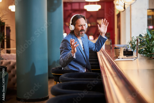 Delighted man enjoying listening to his playlist at hotel lounge photo