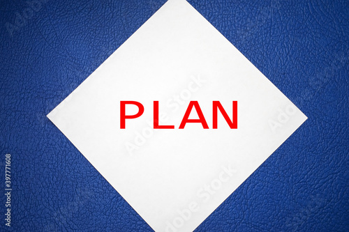 The plan is written on a white sheet of paper that lies on a blue background. Concept photo